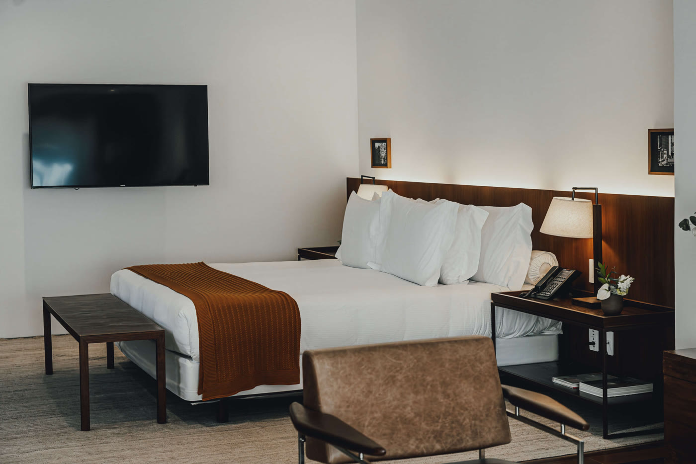 Habitación en Fasano Belo Horizonte con cama king, cabecero de madera oscura y sillón de cuero