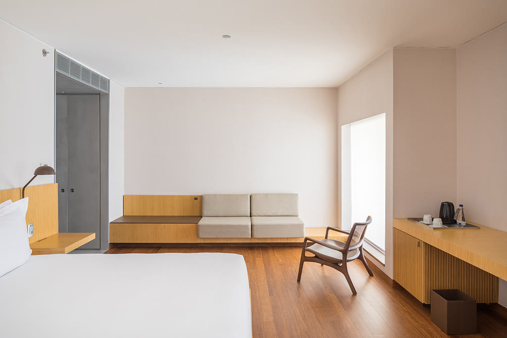 Guest room at B Hotel Brasília with warm wood finishes, a desk, and a seating area