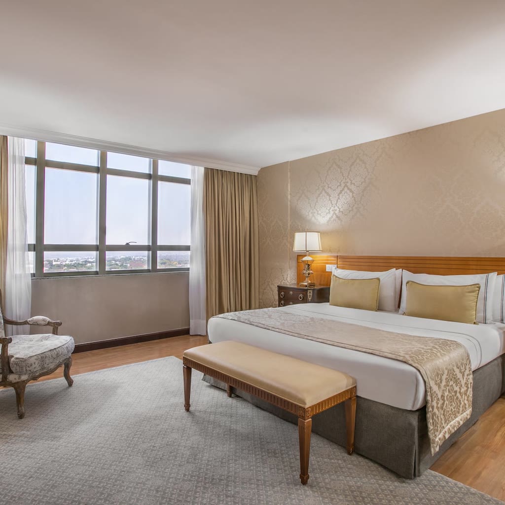 Guest room at Meliá Brasil 21 with a king bed, gold accents, and a city-view window