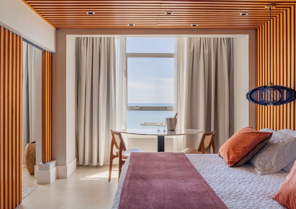 Ocean-view guest room at Praiano Hotel with a bed, table, and slatted wood ceiling