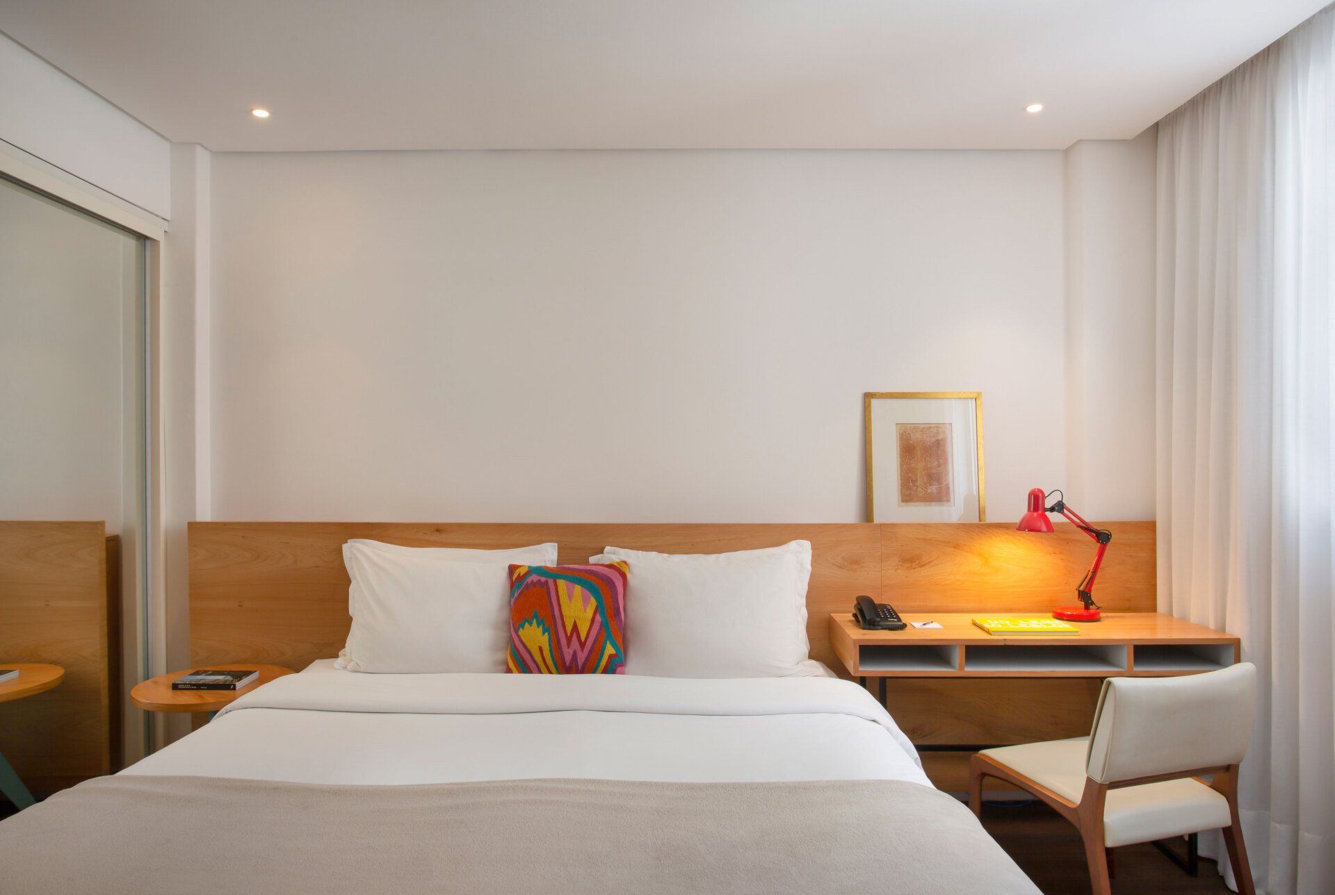 Guest room at Ipanema Inn with wood desk and colorful accent pillow